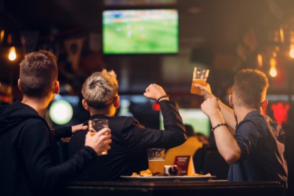 Men celebrating in front of the TV watching football in ABu Dhabi for the FIFA World Cup