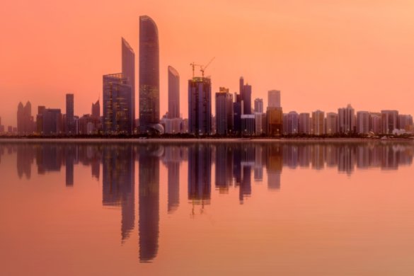 an orange glowing sunset over the abu dhabi corniche skyline