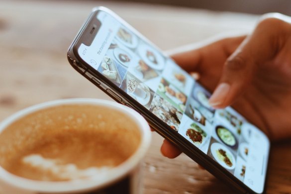 a lady holding a smartphone over a cup of coffee