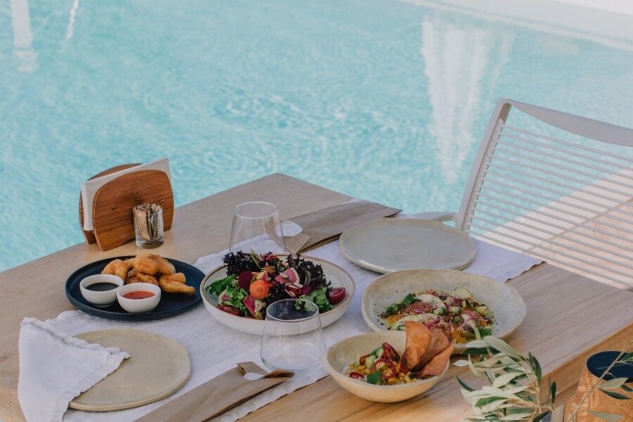 a meal set out on a table beside a swimming pool